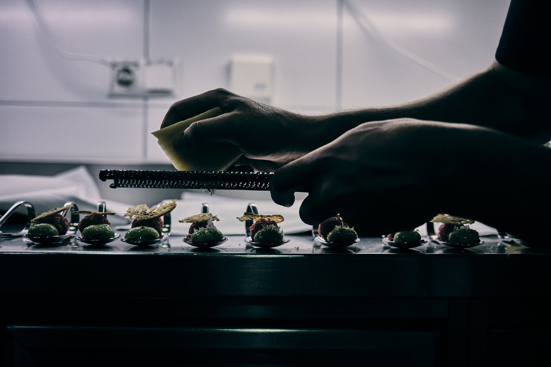 Reportageaufnahme: Parmesan wird über Amouse Bouche Löffel gerieben