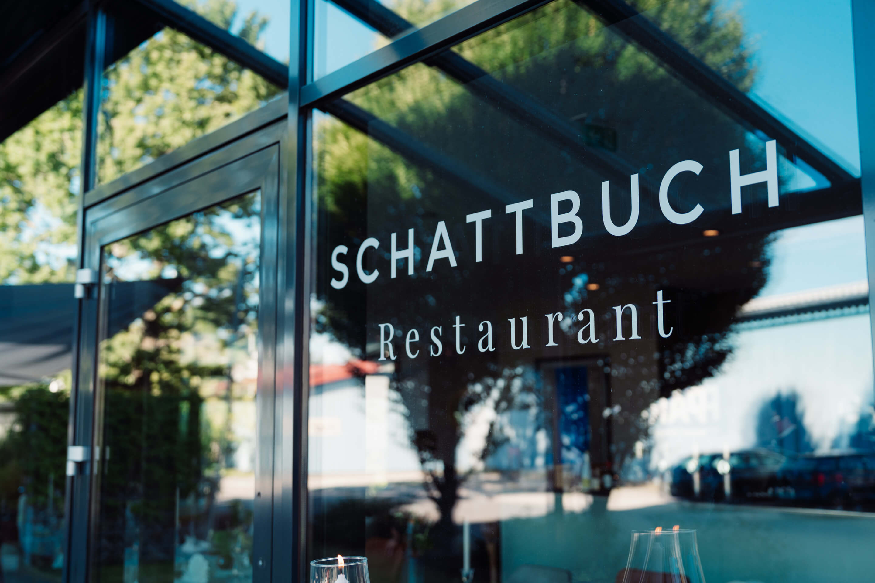 Schattbuch-Restaurant Schriftzug an der Glasfront neben der Eingangstüre.