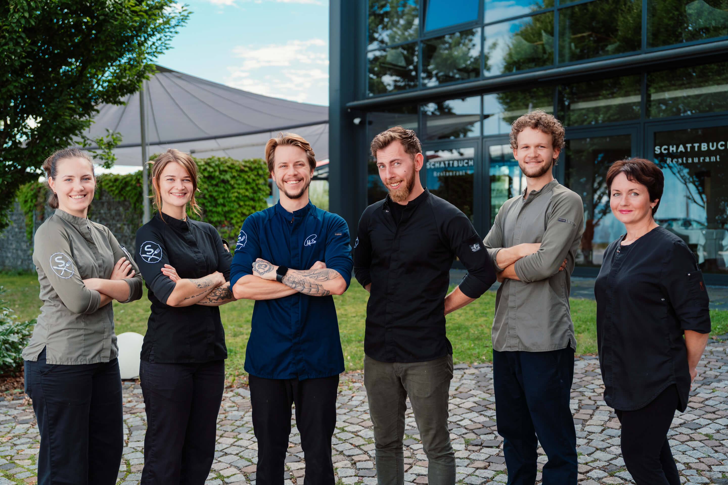 Teamfoto des Küchenteams vor dem Restaurant in Reihe stehend