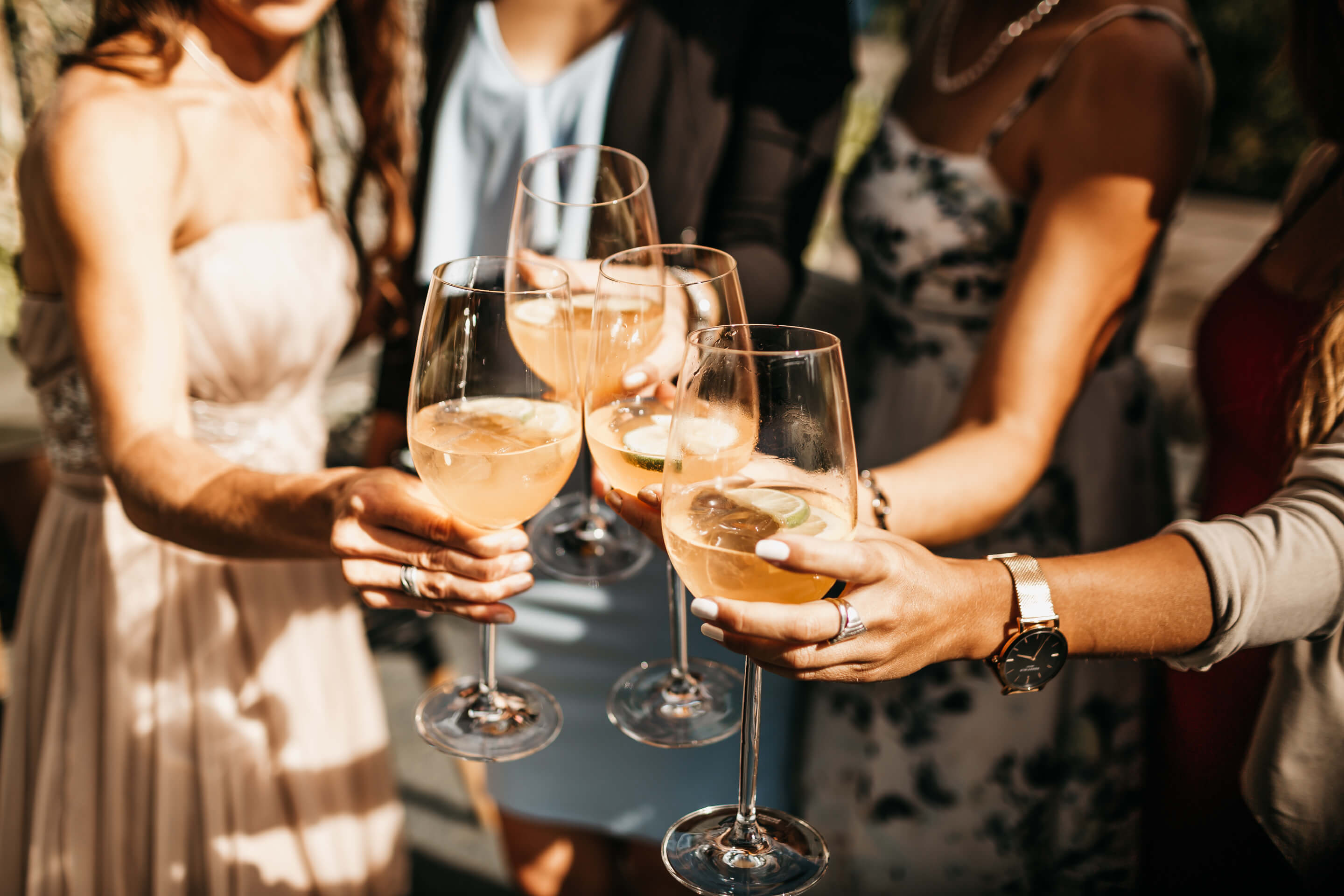 Bild von einer Frauengruppe, die gemeinsam mit ihrem Aperitif anstoßen in Sommerkleidern