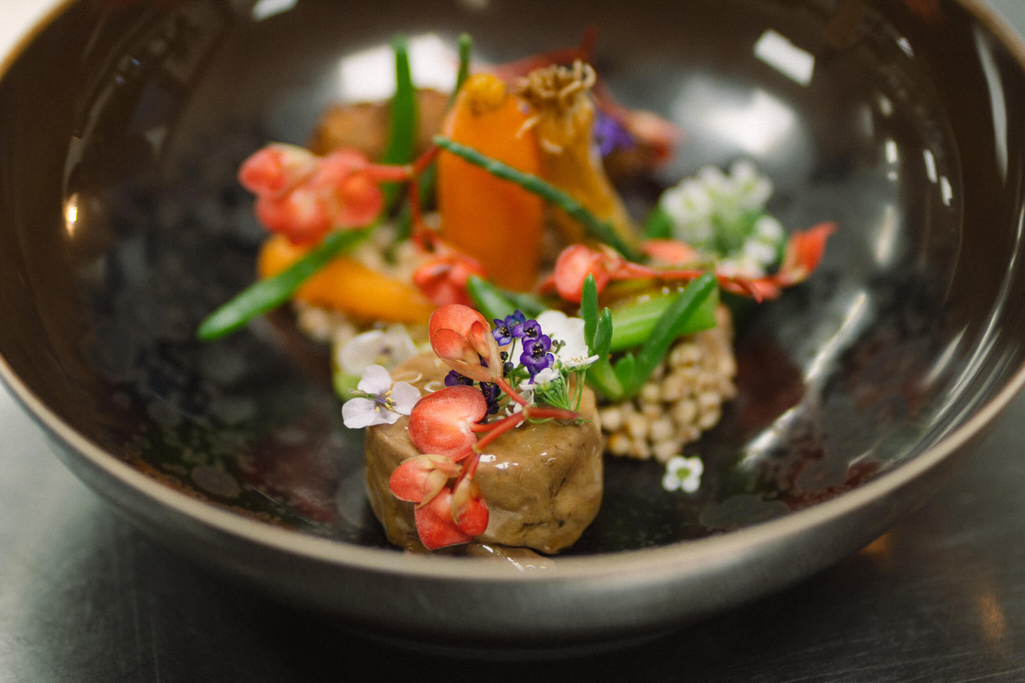 Tiefer Teller, der einer Vase ähnelt, mit Gemüse, Sprossen und Blüten