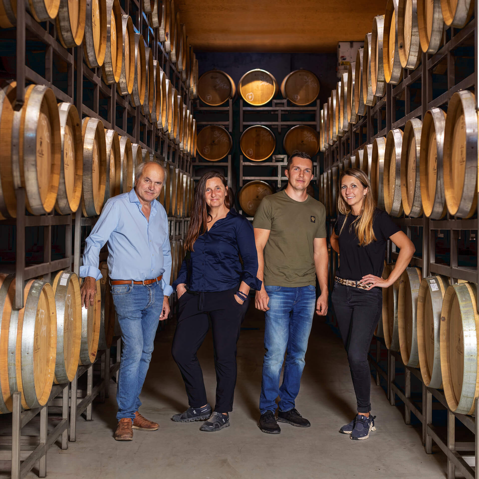 Eine Familie im Fasskeller neben großen Holzfässern