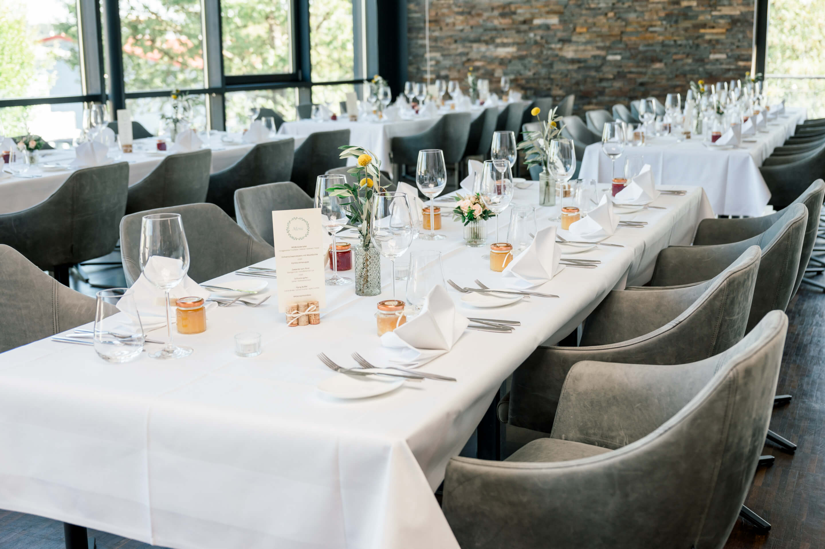 Sommerlich eingedeckte Tafel mit grauen Drehstühlen für eine Hochzeitsgesellschaft