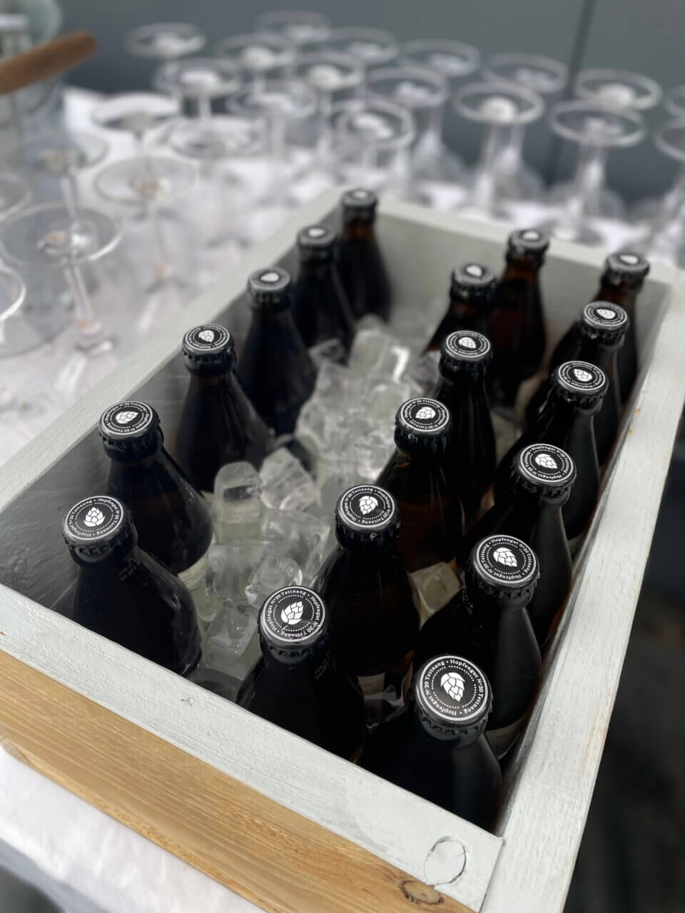Eine Reihe an Bierflaschen in einer Holzkiste mit Eis
