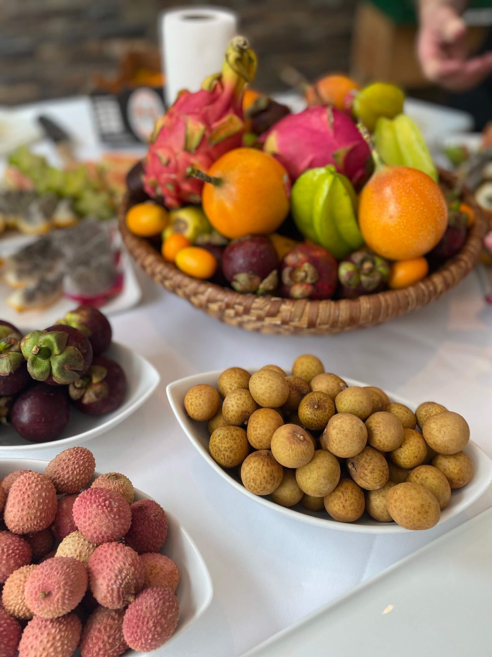 Ein prall gefüllter Obstkorb und mehrere Schalen mit exotischen Früchten